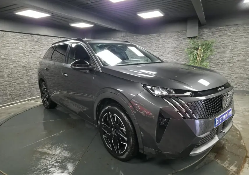 Peugeot 5008 gris métallisé vue 3/4 avant droit avec jantes alliage noires et calandre distinctive.