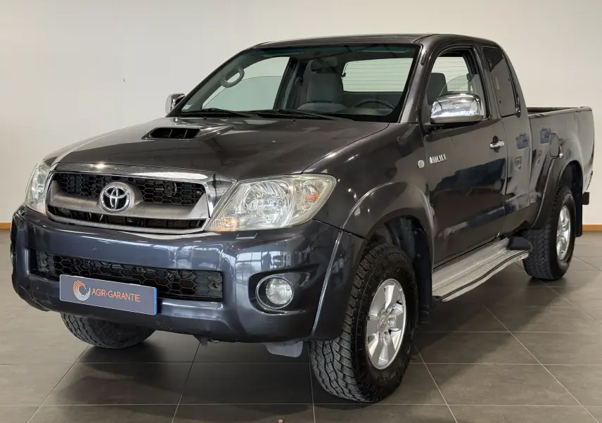 Toyota Hilux X-Tra Cabine gris vu en 3/4 avant droit, avec calandre chromée et prise d'air sur le capot.