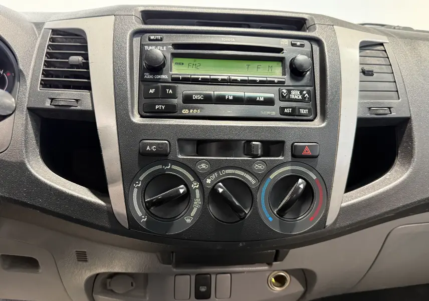 Tableau de bord du Toyota Hilux X-Tra Cabine 2009, vue frontale centrée sur la radio et les commandes de climatisation.