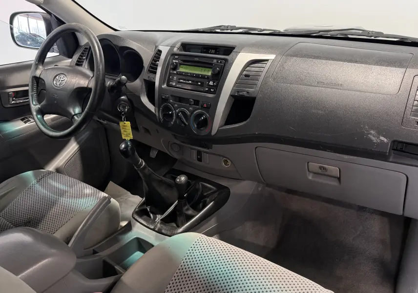 Vue intérieure côté conducteur du tableau de bord gris et de la boîte manuelle du Toyota Hilux X-Tra Cabine 2009.