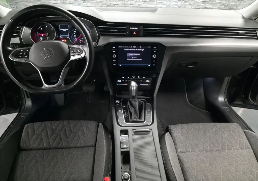 Vue intérieure avant de la Volkswagen Passat SW 2024, tableau de bord noir avec volant multifonction et console centrale moderne.