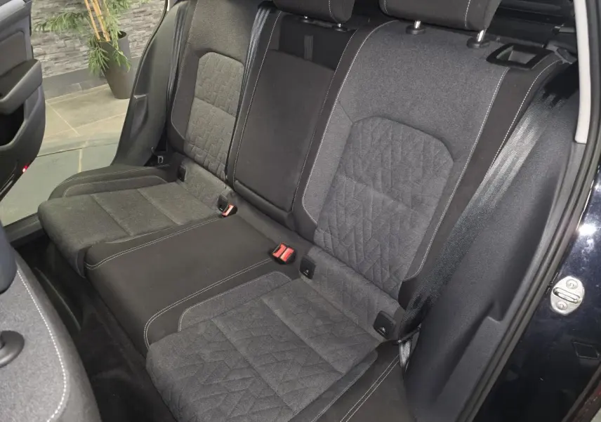 Vue intérieure côté arrière droit de la banquette tissu gris foncé avec surpiqûres blanches de la Volkswagen Passat SW noire 2024.