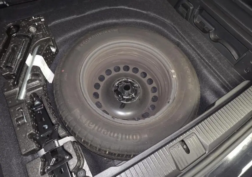 Vue rapprochée du coffre de la Volkswagen Passat SW 2024 montrant la roue de secours et les outils de changement de pneu.