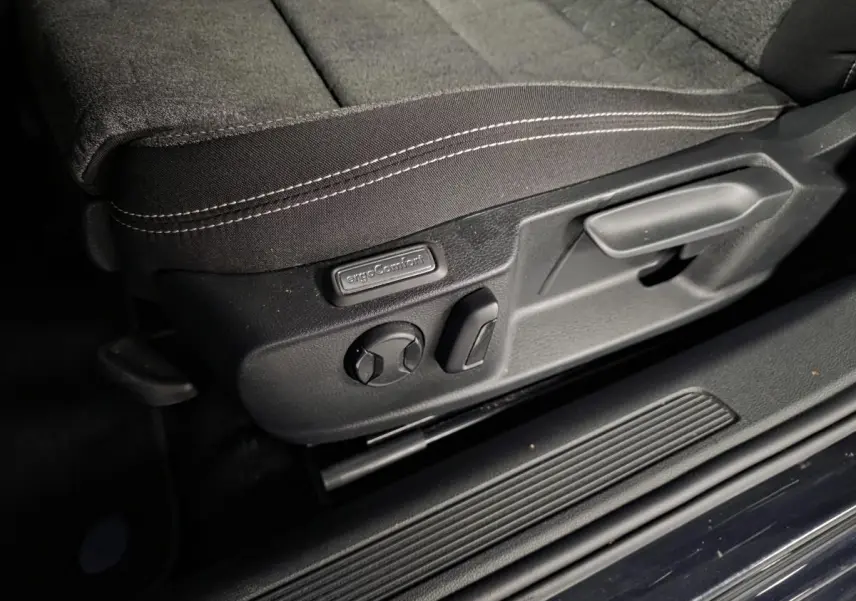 Détail des commandes de réglage du siège avant en tissu noir de la Volkswagen Passat SW 2024 côté gauche.