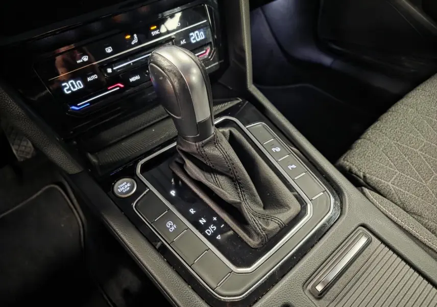 Gros plan sur la console centrale noire de la Volkswagen Passat SW 2024, mettant en valeur le levier de vitesse automatique et les commandes adjacentes.