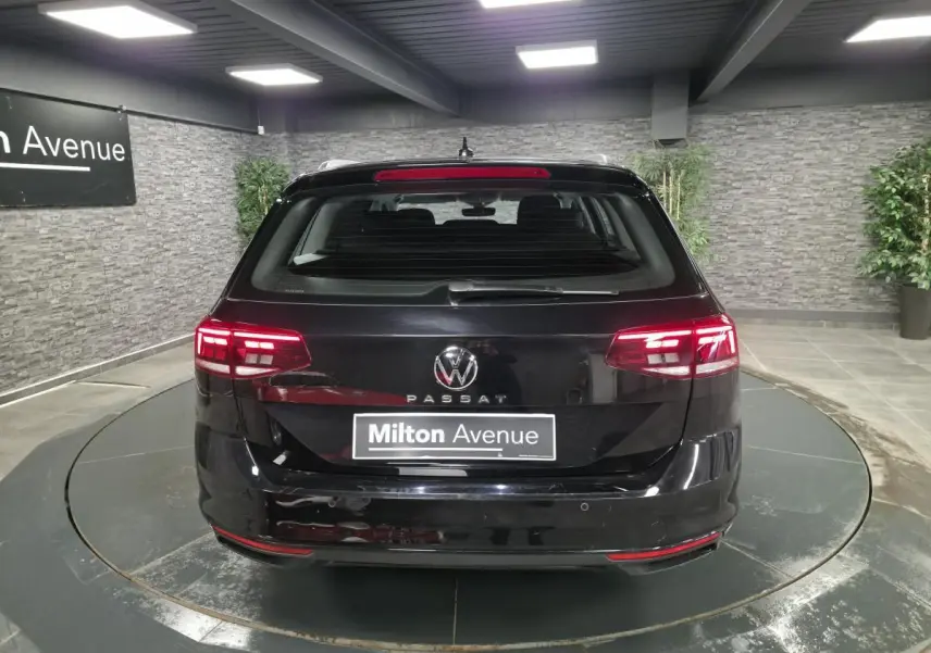 Vue arrière d'une Volkswagen Passat SW noire avec feux LED allumés dans un showroom intérieur.