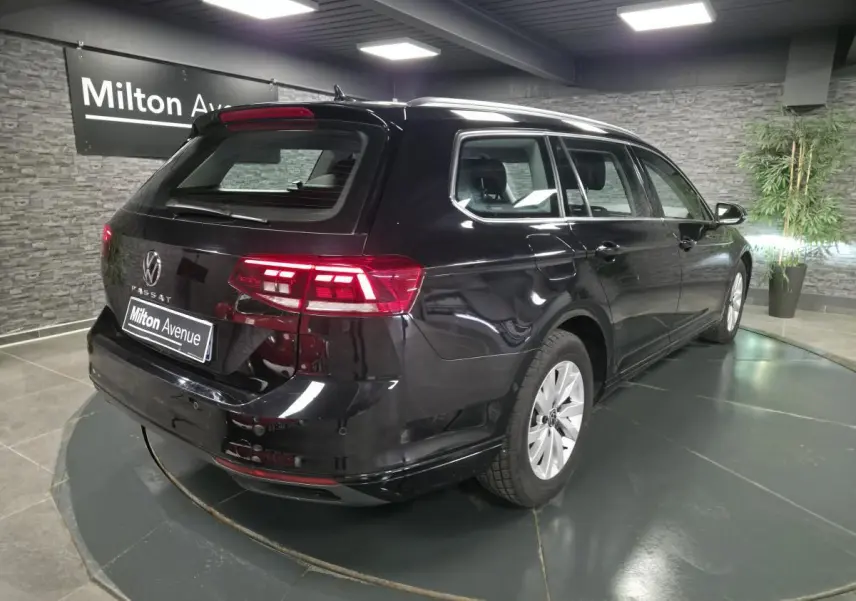 Vue 3/4 arrière droite d'une Volkswagen Passat SW noire avec feux arrière LED allumés en showroom.