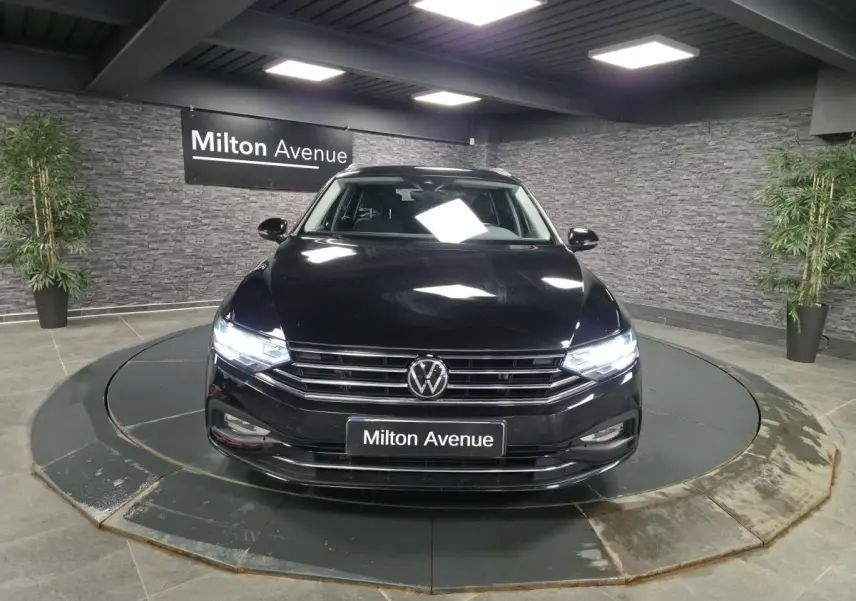 Vue avant d'une Volkswagen Passat SW noire avec phares allumés sur plateau tournant intérieur.