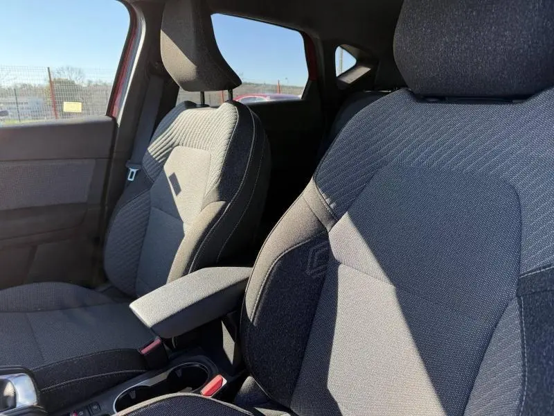 Gros plan sur les sièges avant gris du Renault Captur 2025, montrant les textures et l'accoudoir central.