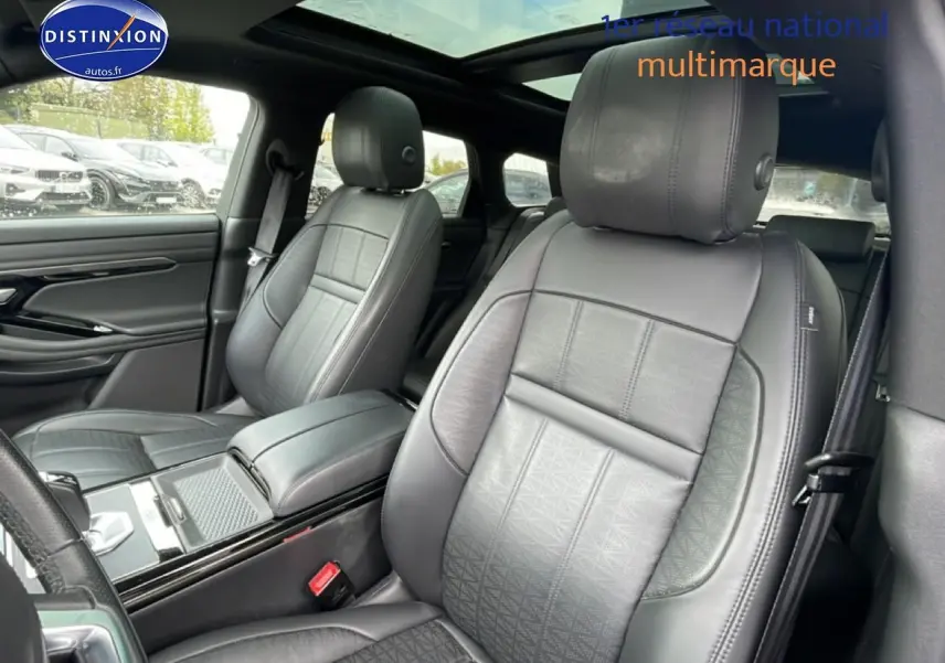 Vue intérieure sur les sièges avant en cuir noir du Range Rover Evoque 2020 avec toit panoramique et accoudoir central.