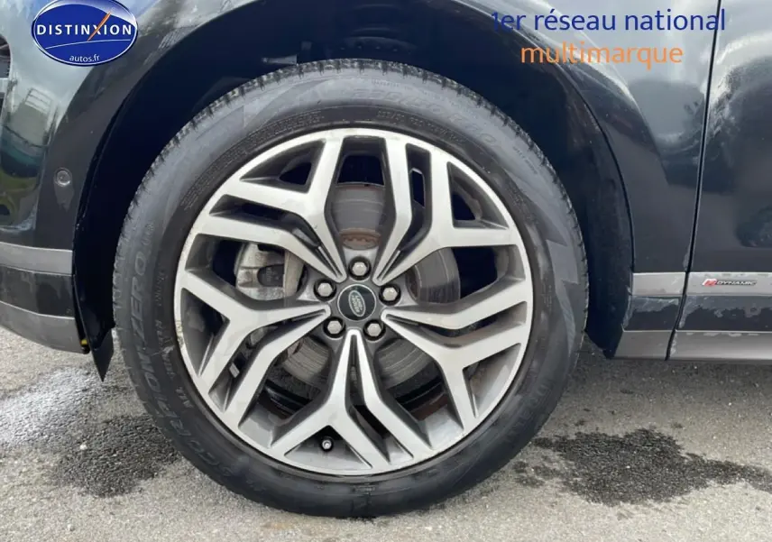 Gros plan sur la roue avant gauche du Range Rover Evoque noir avec jante alu et badge R-Dynamic visible.