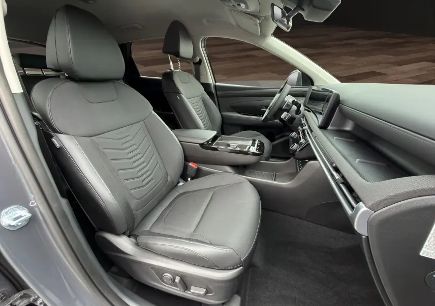 Intérieur avant droit du Hyundai Tucson 1.6 Hybrid 239 Creative 2026 en gris foncé, sièges tissu et tableau de bord moderne.