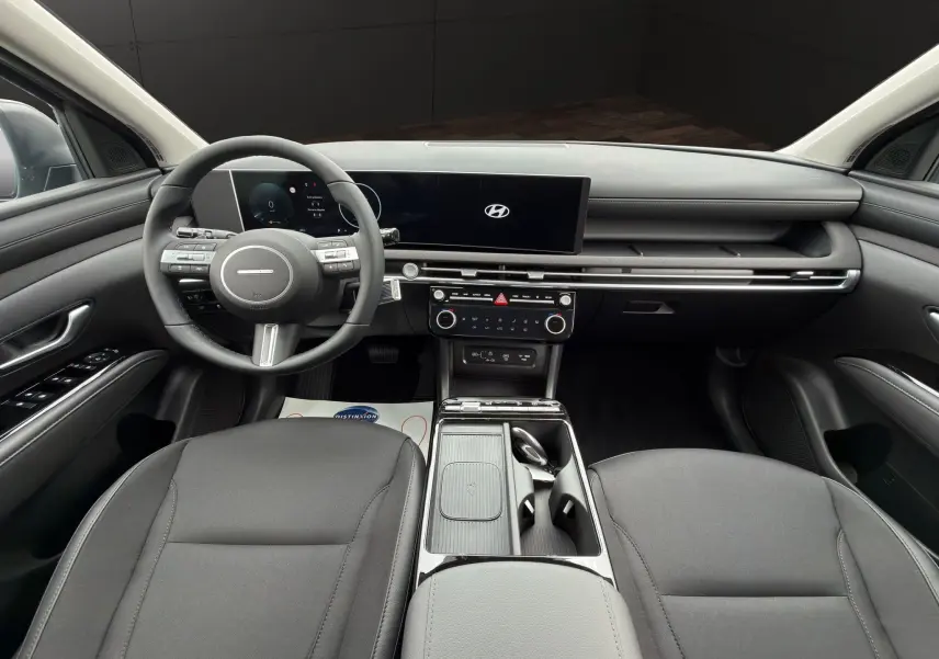 Vue intérieure avant du Hyundai Tucson 1.6 Hybrid gris foncé, avec tableau de bord digital et volant multifonctions cuir.