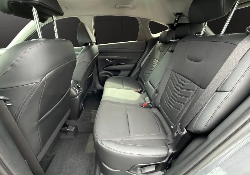Vue intérieure arrière côté droit du Hyundai Tucson 1.6 Hybrid 239 Creative 2026 avec sièges noirs en tissu et cuir.