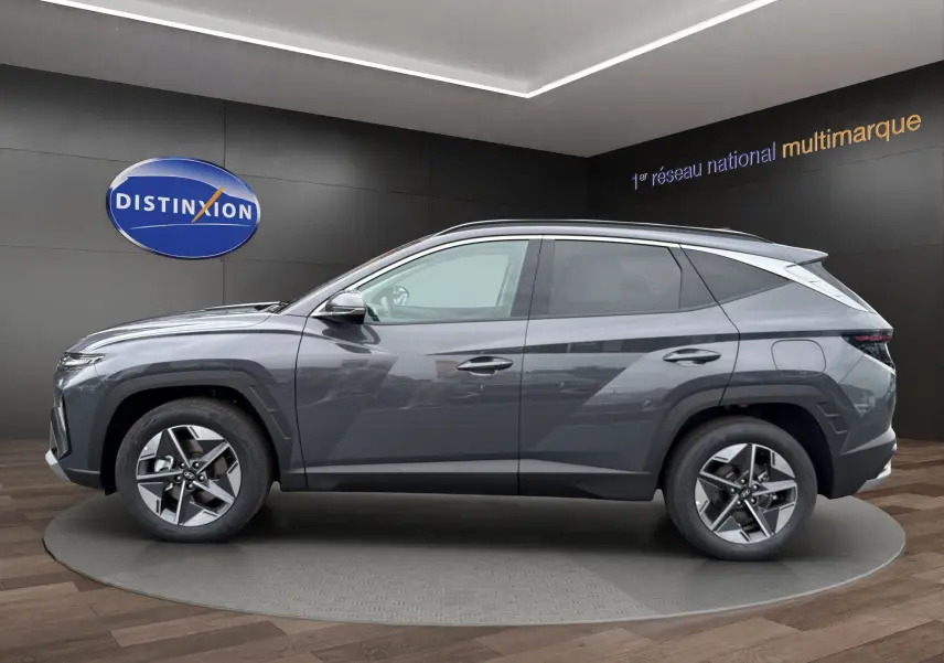 Vue de profil côté gauche du Hyundai Tucson 1.6 Hybrid gris foncé avec jantes alliage et lignes anguleuses marquées.