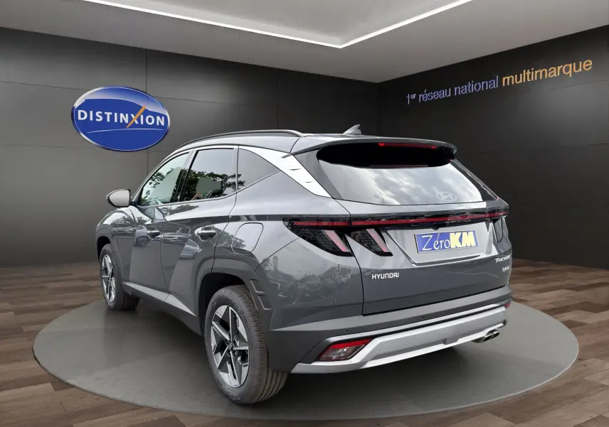 Vue 3/4 arrière d'un Hyundai Tucson gris foncé avec feux arrière LED et jantes alliage, en showroom.