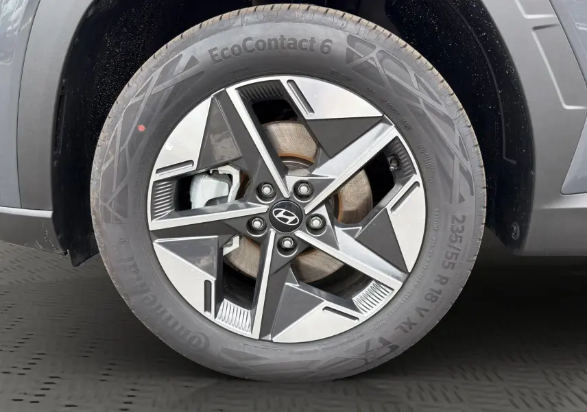 Gros plan sur la roue avant gauche du Hyundai Tucson gris foncé, avec jante alliage à design géométrique moderne.