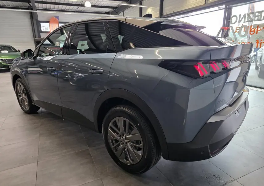 Vue 3/4 arrière droit d’un Peugeot 3008 hybride bleu avec feux arrière à LED en forme de griffes et jantes alliage 18 pouces.