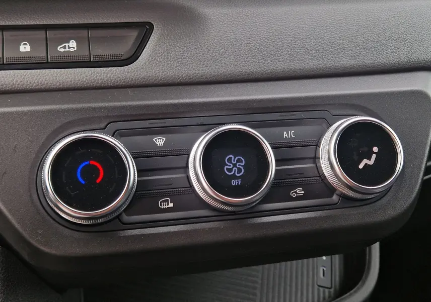 Gros plan sur les commandes de climatisation du Renault Master blanc, avec réglages circulaires et affichages numériques.
