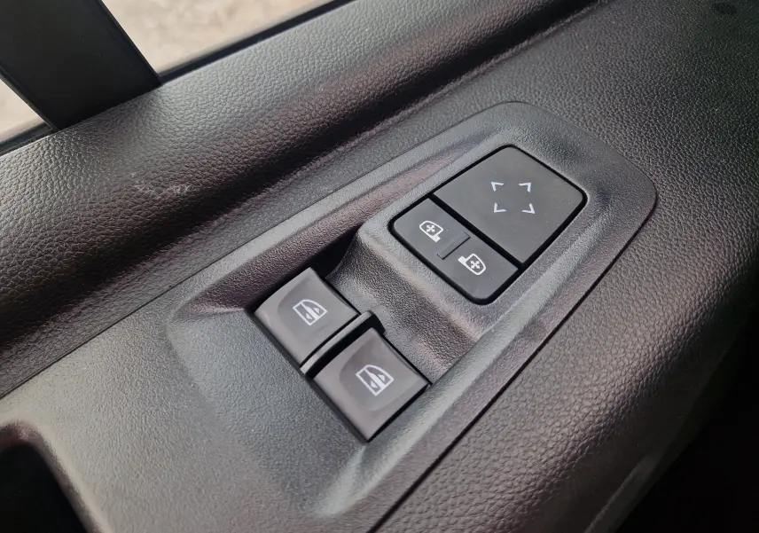 Gros plan sur les commandes de réglage des vitres et des rétroviseurs côté conducteur du Renault Master blanc 2026.