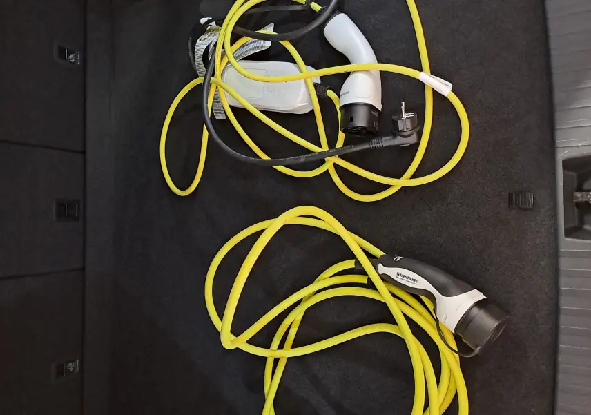 Vue plongeante sur le coffre d'un Skoda Kodiaq gris perle avec câbles de recharge hybrides jaunes enroulés.
