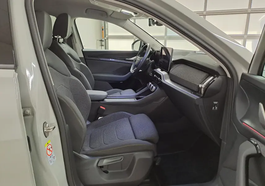 Vue intérieure côté conducteur du Skoda Kodiaq gris perle 2025, avec sièges tissu et tableau de bord moderne.