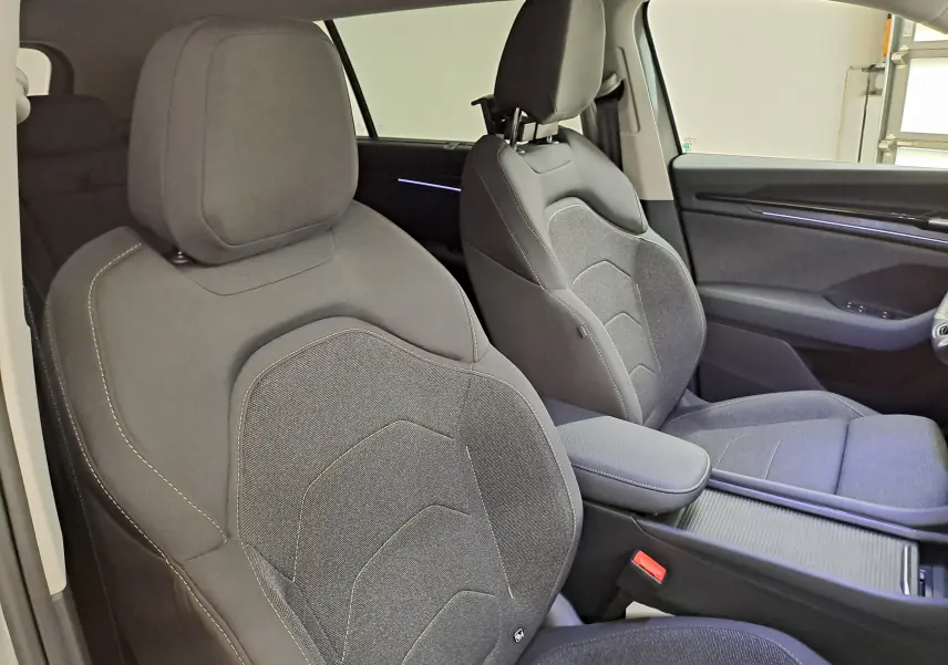 Vue intérieure côté avant droit du Skoda Kodiaq 2025, sièges tissu gris foncé avec surpiqûres claires.