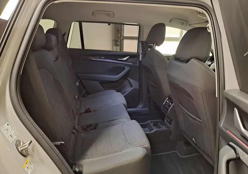 Vue intérieure côté gauche des sièges arrière du Skoda Kodiaq gris perle 2025, montrant l'habitacle spacieux et les finitions tissu.