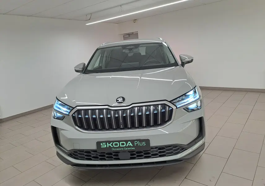 Vue avant d'un Skoda Kodiaq gris perle avec phares LED allumés dans un intérieur neutre.