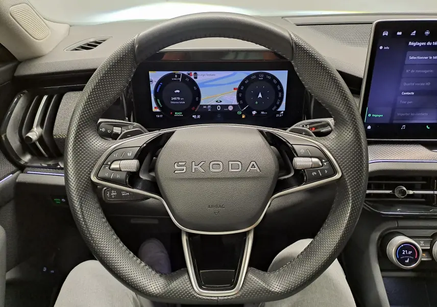 Vue intérieure centrée sur le volant perforé SKODA d'un KODIAQ 2025 avec tableau de bord numérique et écran tactile.