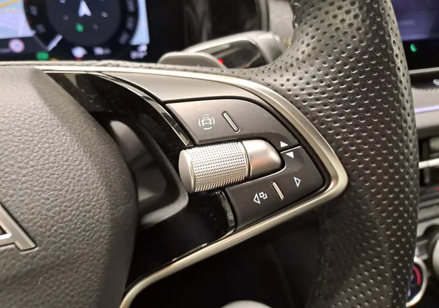 Gros plan sur les commandes multifonctions en métal et cuir perforé du volant d’un Skoda Kodiaq gris perle 2025.