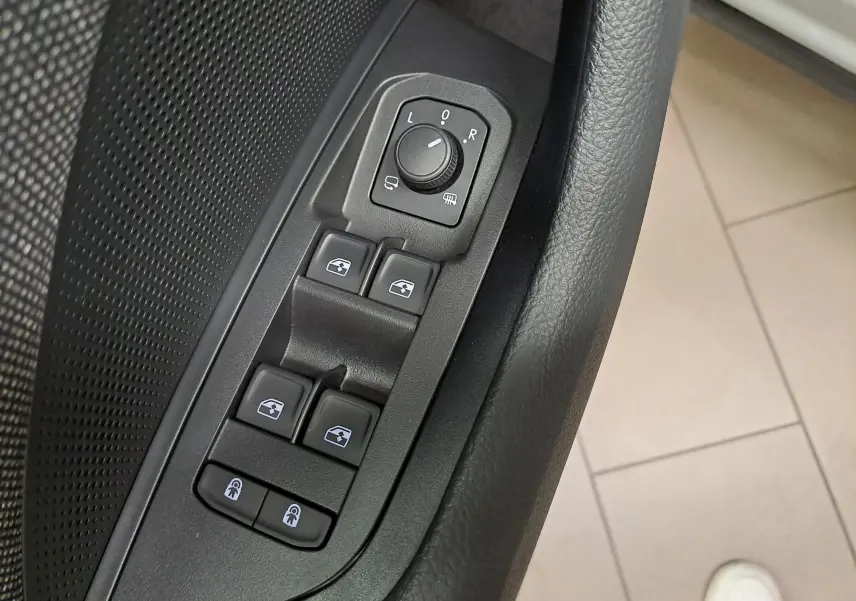 Gros plan sur les commandes de lève-vitres et réglage des rétroviseurs côté conducteur du Skoda Kodiaq gris perle.