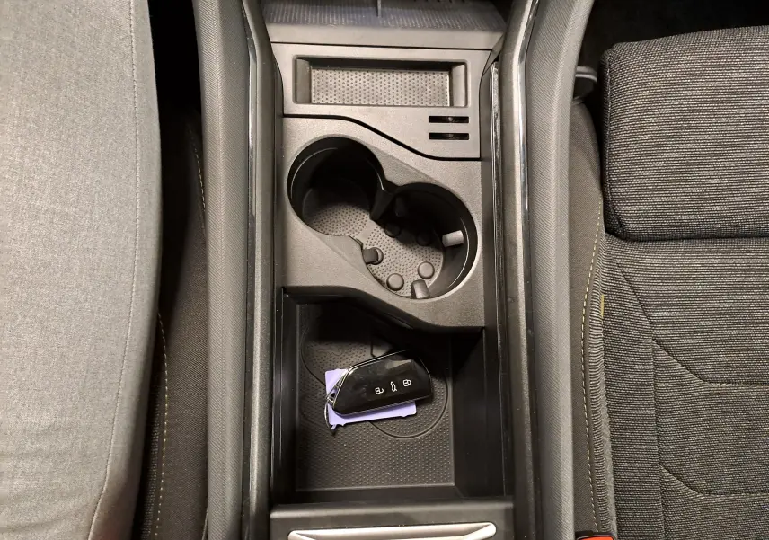 Vue plongeante sur la console centrale noire du Skoda Kodiaq 2025, avec porte-gobelets et clé de voiture posée.