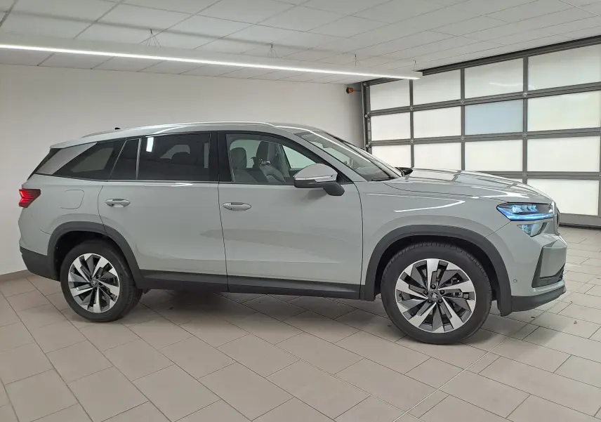 Vue de profil côté gauche du Skoda Kodiaq gris perle 2025 avec jantes alliage 19'' Lefka anthracite en intérieur showroom.