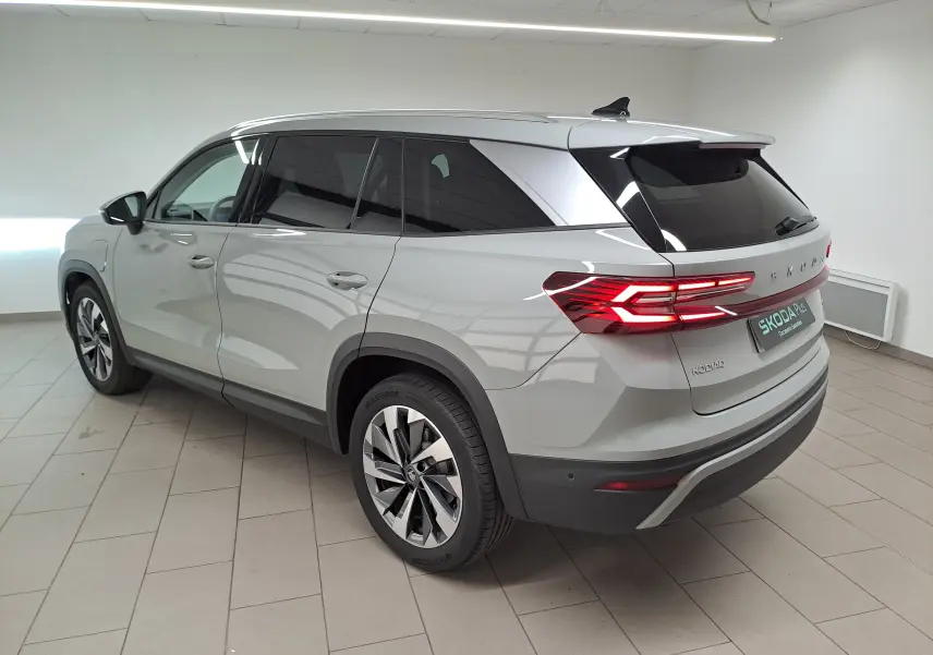 Vue 3/4 arrière droite d'un Skoda Kodiaq gris perle avec feux arrière allumés et jantes alliage 19 pouces.