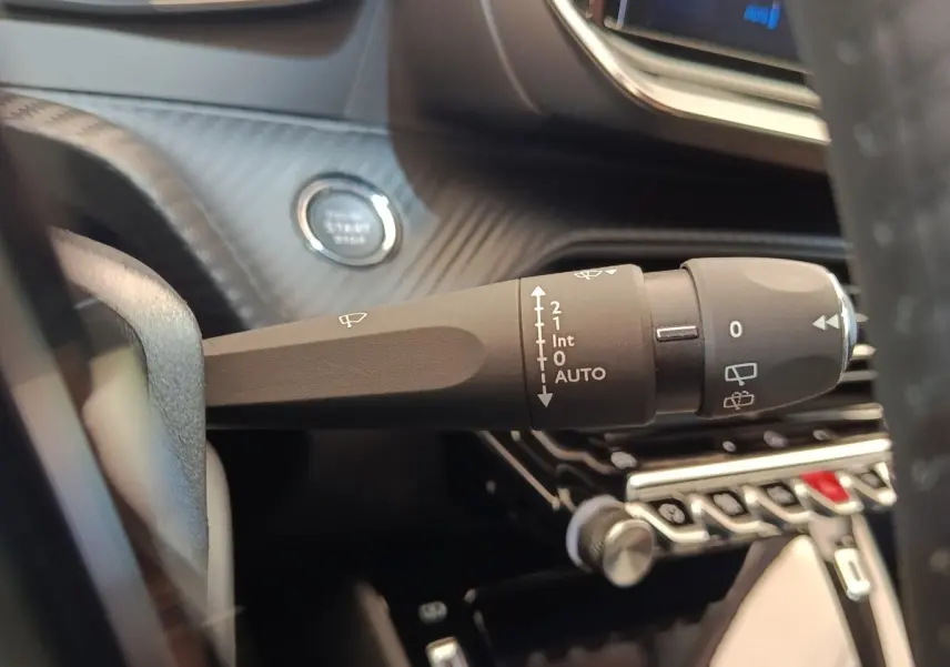 Gros plan sur la commande d’essuie-glace côté droit du tableau de bord d’une Peugeot 208 électrique blanche 2024.