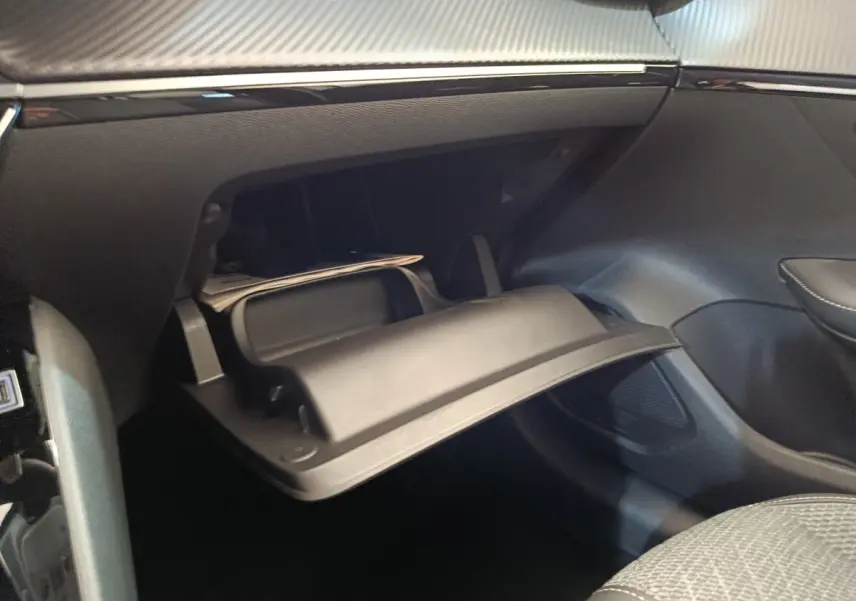 Vue intérieure du coffre à gants ouvert côté passager de la Peugeot 208 électrique blanche, montrant le rangement réfrigéré.