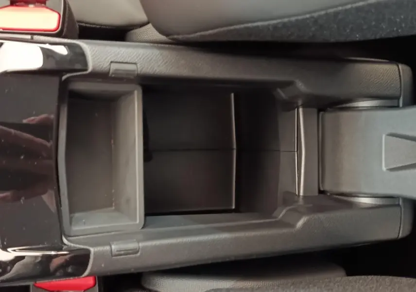 Vue plongeante sur le rangement central noir de la Peugeot 208 électrique blanche, intérieur moderne et épuré.