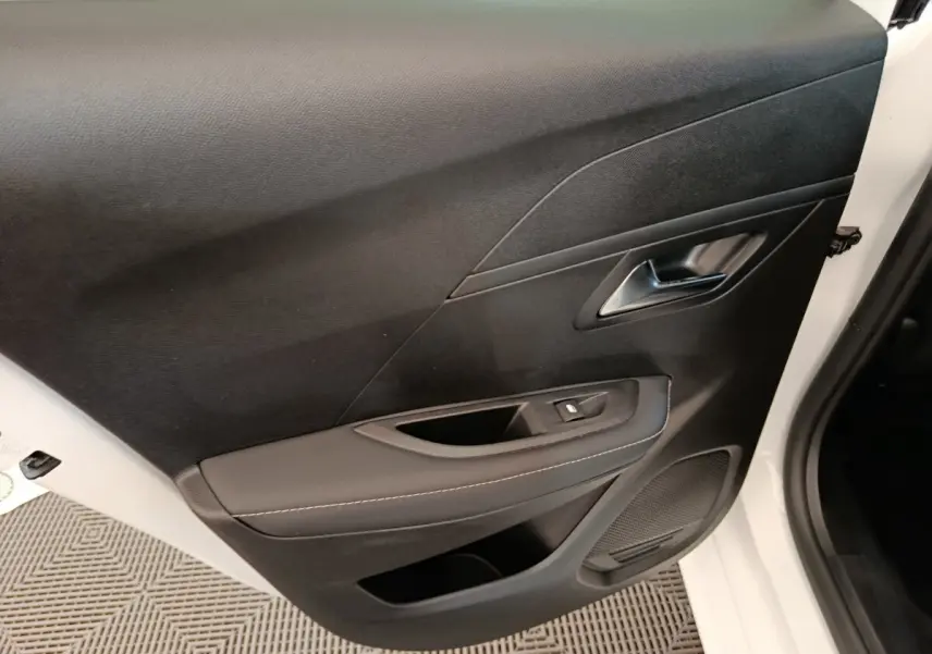 Vue rapprochée de la porte intérieure côté conducteur noire de la Peugeot 208 électrique blanche 2024.