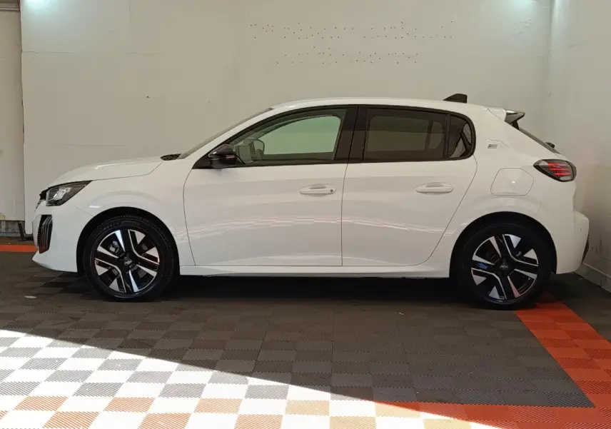 Peugeot 208 électrique blanche vue de profil côté gauche, avec jantes noires et détails bleus sur les roues.