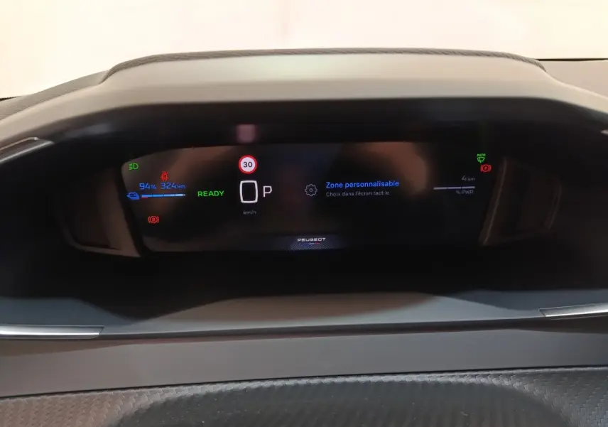Affichage numérique du combiné instruments de la Peugeot 208 électrique 2024, avec indicateurs batterie et vitesse.