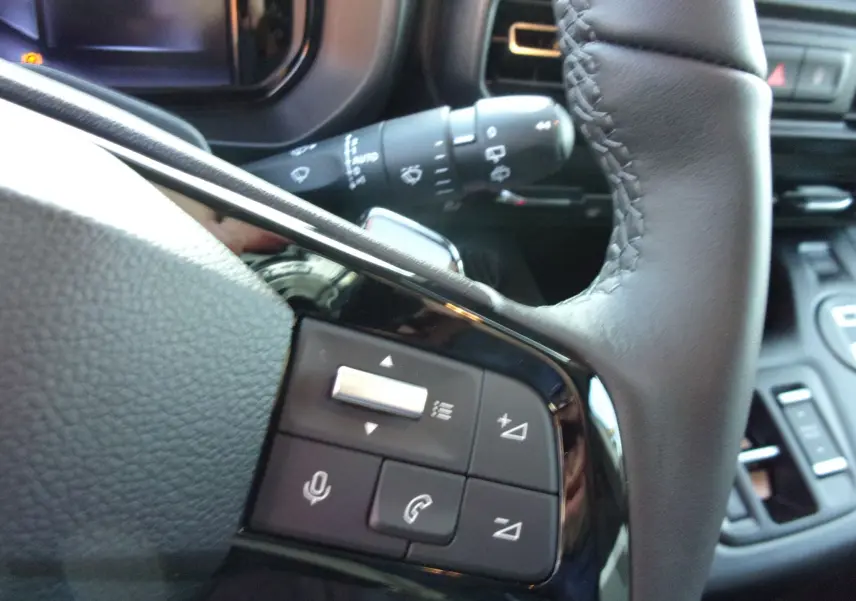 Gros plan sur les commandes au volant en cuir noir du Citroën Berlingo 2025, version diesel gris Artense.