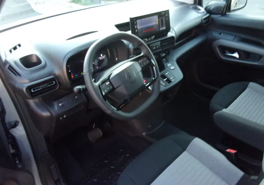 Vue intérieure côté conducteur du Citroën Berlingo 2025 gris Artense, avec tableau de bord et écran tactile central.
