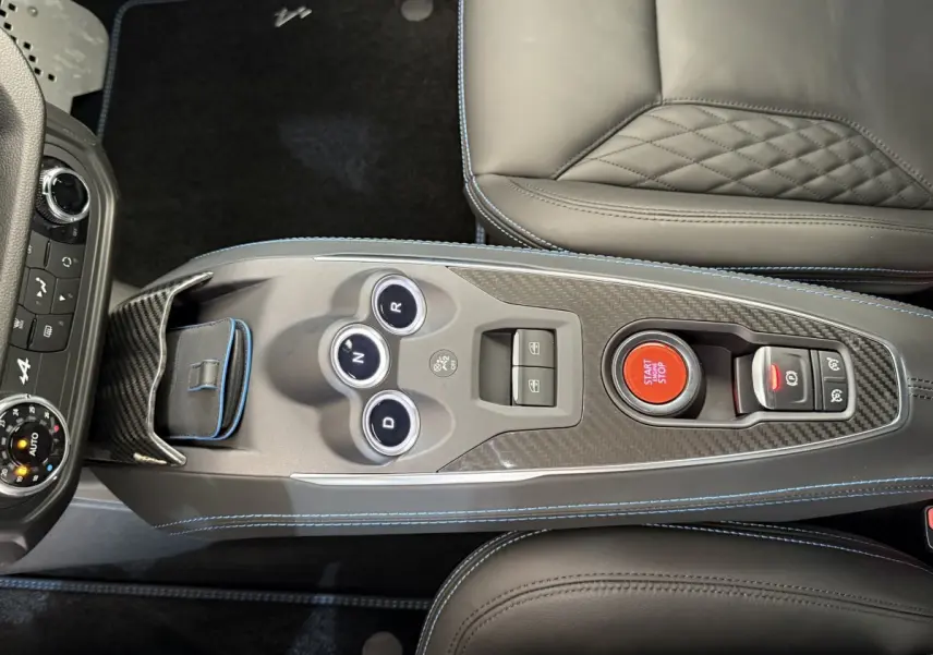 Vue plongeante sur la console centrale en carbone de l'Alpine A110 Legende 2019 avec bouton start/stop rouge et cuir gris.