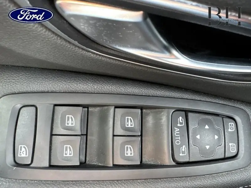 Gros plan sur les commandes de lève-vitres et rétroviseurs électriques dans une Renault Grand Scenic noir étoilé.