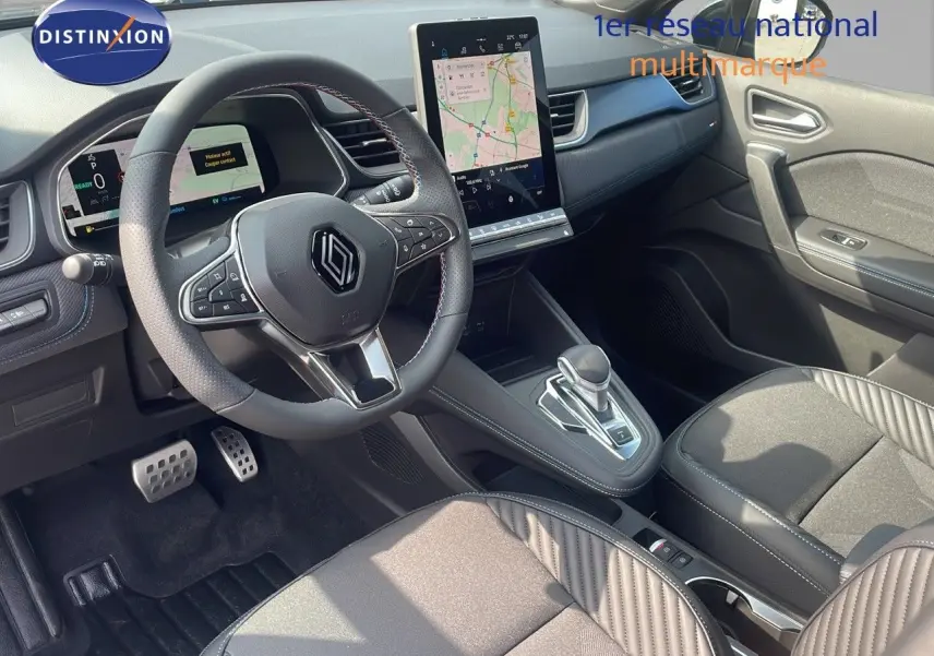 Intérieur du Renault Captur E-Tech hybride 2025 vu côté passager, tableau de bord noir avec écran tactile et sièges bi-matière.