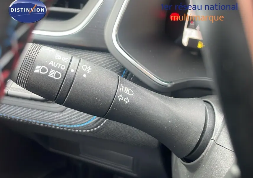 Gros plan sur la commande des feux et clignotants du Renault Captur E-Tech gris cassiopée, intérieur avec surpiqûres bleues.