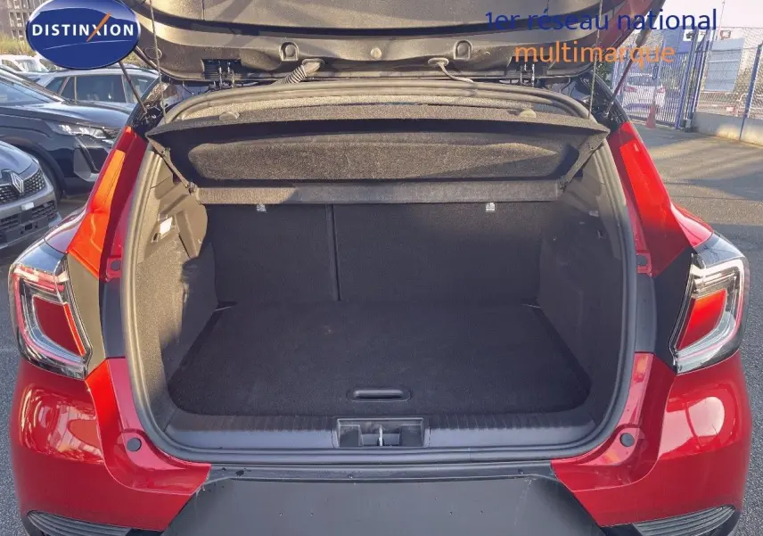 Coffre ouvert vu de l'arrière d'un Renault Captur E-Tech hybride rouge passion avec toit noir, montrant l'espace de chargement vide.