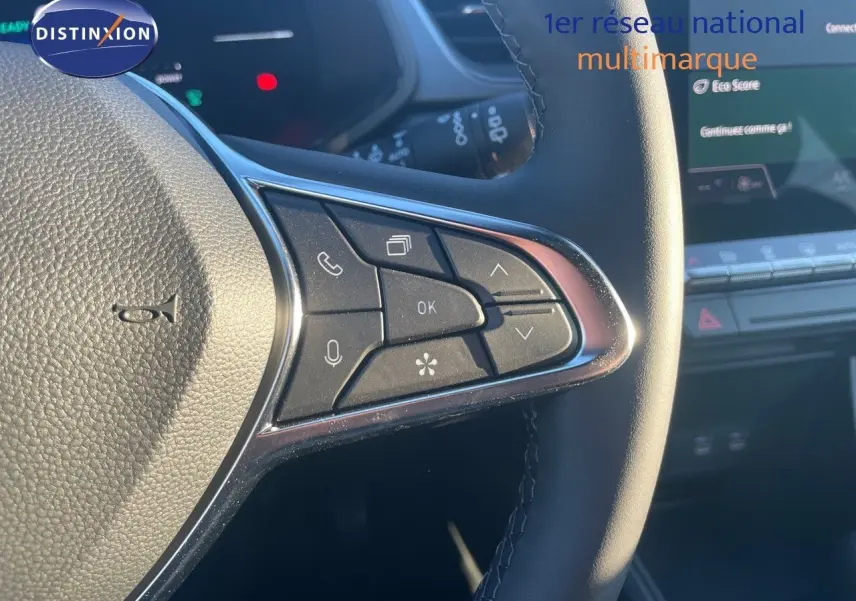 Gros plan sur les commandes au volant du Renault Captur E-Tech hybride rouge, avec tableau de bord numérique en arrière-plan.