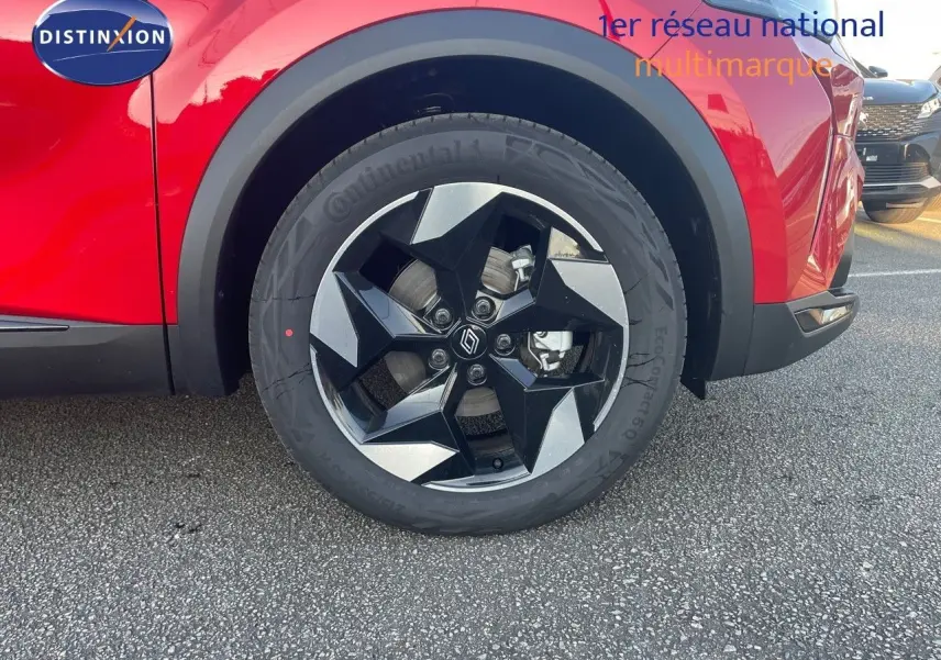 Gros plan sur la roue avant gauche d’un Renault Captur rouge passion avec jante noire et argentée au design géométrique.